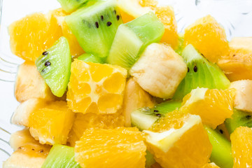 healthy breakfast salad of orange banana and kiwi in a glass dish on a white background fitness...
