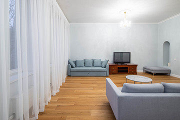 Living room with furniture in apartment. Modern interior in light tones. Window and white curtain.