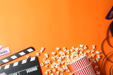 Flat lay composition with clapperboard and cinema tickets on orange background, space for text