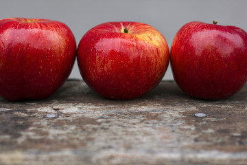 Three red apples on a gray background