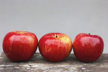 Three red apples on a gray background