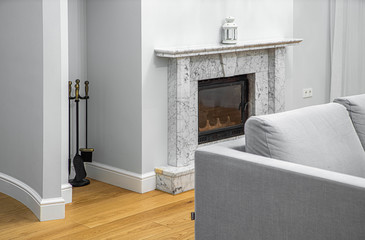 Living room with furniture in apartment. Modern interior in light tones. Close-up of fireplace.