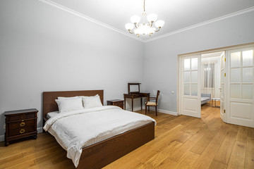 Modern interior in light tones. Bedroom with wooden furniture. White door.