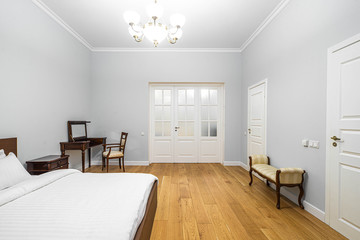 Modern interior in light tones. Bedroom with wooden furniture. White doors.