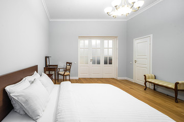Modern interior in light tones. Bedroom with wooden furniture. White door.