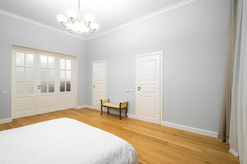 Modern interior in light tones. Bedroom with wooden furniture. White door.