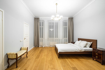 Modern interior in light tones. Bedroom with wooden furniture. White curtain.