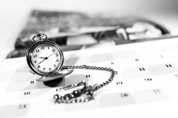 Old pocket watch on calendar, shallow depth of field, copy space, conceptual image of passing time...