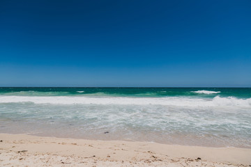 view of Scarborough beach, one of the most popular beaches near Perth on the Indian Ocean, with intense turquoise water and ships in the distance