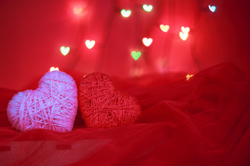 Holiday concept valentine's day. Textile hearts made of cotton yarn on a red background. Heart bokeh in the background. Holiday card.