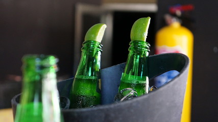 Few bottles of a beer with lime in an ice bucket.