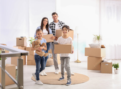 Happy family in room with cardboard boxes on moving day