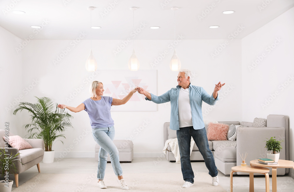 Poster happy mature couple dancing together in living room