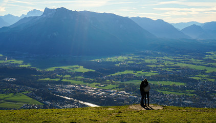 Couple kiss at the top Untersberg mountain and background with aerial panorama of Salzburg in Austria.