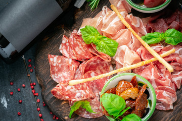 Italian meat appetizers and wine on a wooden tray. Wine snack Antipasto-salami, prosciutto, slices...