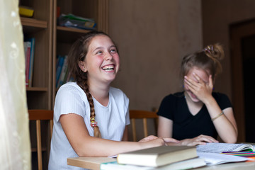 Two sisters   learning lessons at   table.