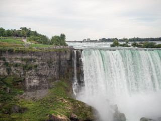 Fototapeta premium Niagara Falls, New York state, United States of America and Canada - edge of Niagara falls, town from American and Canadian city side, falling water and mist