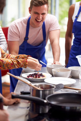 Students Watching Female Teacher Decorating Pancake In Cookery Class