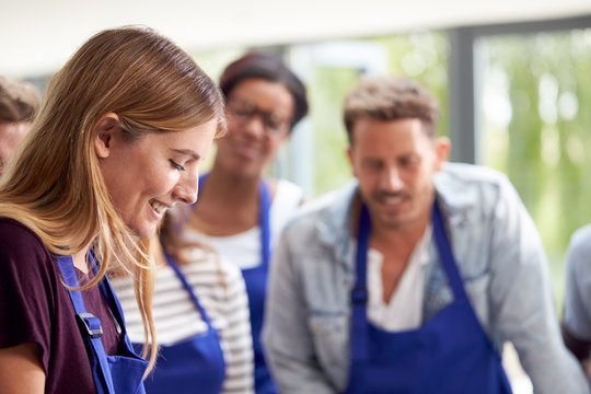 Students Watching Female Teacher Following Recipe In Cookery Class