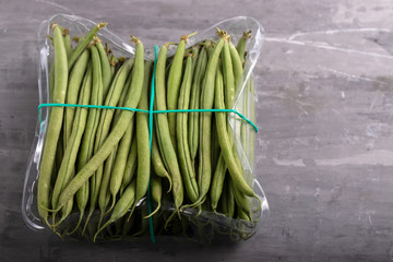 green beans in plastic box on ceramic background