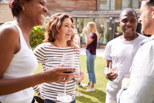 Group Of Multi-Cultural Friends Relaxing And Drinking Wine At Summer Garden Party Together