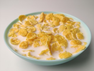 cornflakes with milk in a blue plate on a white background. Delicious healthy Breakfast.