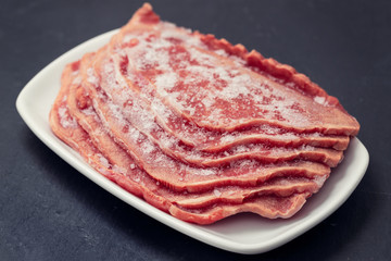 frozen meat on white dish on ceramic background