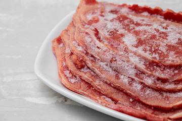 frozen meat on white dish on ceramic background