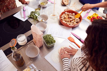 Close Up Of Female Teacher Demonstrating How To Use Dough To Make Flatbread In Cookery Class