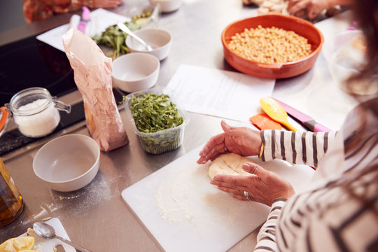 Close Up Of Female Teacher Demonstrating How To Use Dough To Make Flatbread In Cookery Class