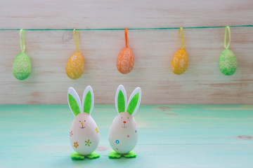 Easter holiday concept with cute bunnies toys and row of Easter eggs on rabbits in vintage wooden background