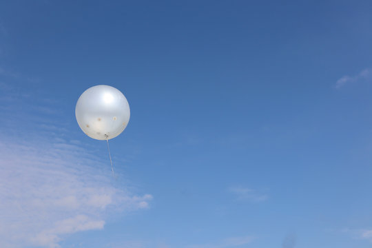 White balloons in the blue sky with cloud background.