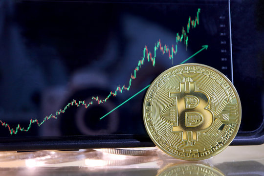 Closeup Golden Bitcoin With Stocks Graph Climb Higher In Background. Business Finance And Cryptocurrency Money Digital Online Concept.