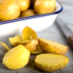 Raw potatoes in wooden bowl on black background 