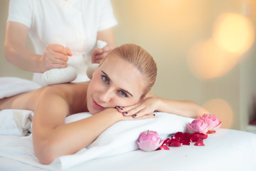 Obraz na płótnie Canvas Young caucasian woman with thick eyebrows and perfect skin at white background,facial massage,massage,towel on head,skin care,treatment.beautiful girl relaxes in the spa salon.Spa and massage concept.