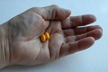 multiple colors pills in hand on white background, Taking Your Medication