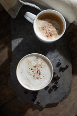 Hot coffee cup and coffee beans on wooden table..