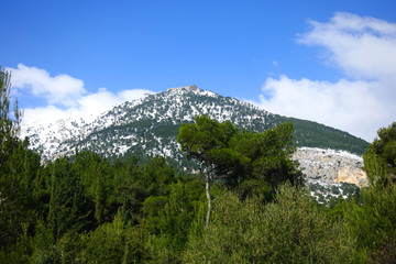 Winter photo of mount Parnitha covered with slight snow and deep blue cloudy sky on a sunny morning