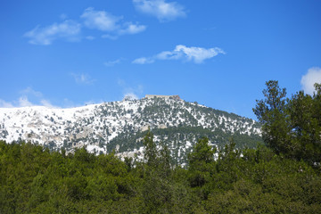 Winter photo of mount Parnitha covered with slight snow and deep blue cloudy sky on a sunny morning