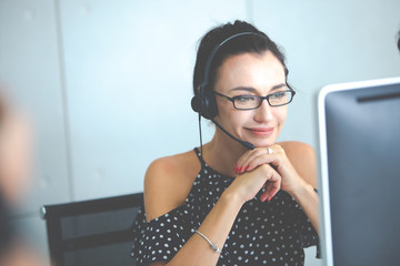 Beautiful consultant of call center in headphones.  Portrait of smiling female customer using...