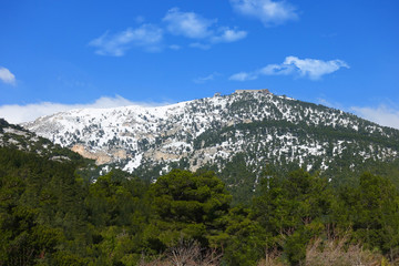 Winter photo of mount Parnitha covered with slight snow and deep blue cloudy sky on a sunny morning
