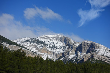 Winter photo of mount Parnitha covered with slight snow and deep blue cloudy sky on a sunny morning