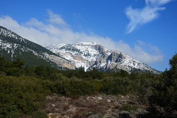 Fototapeta na wymiar Winter photo of mount Parnitha covered with slight snow and deep blue cloudy sky on a sunny morning