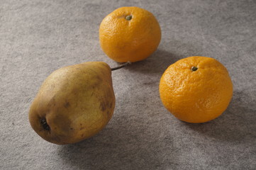 Fruits, mandarin and pear lie on a gray background. Healthy eating concept.