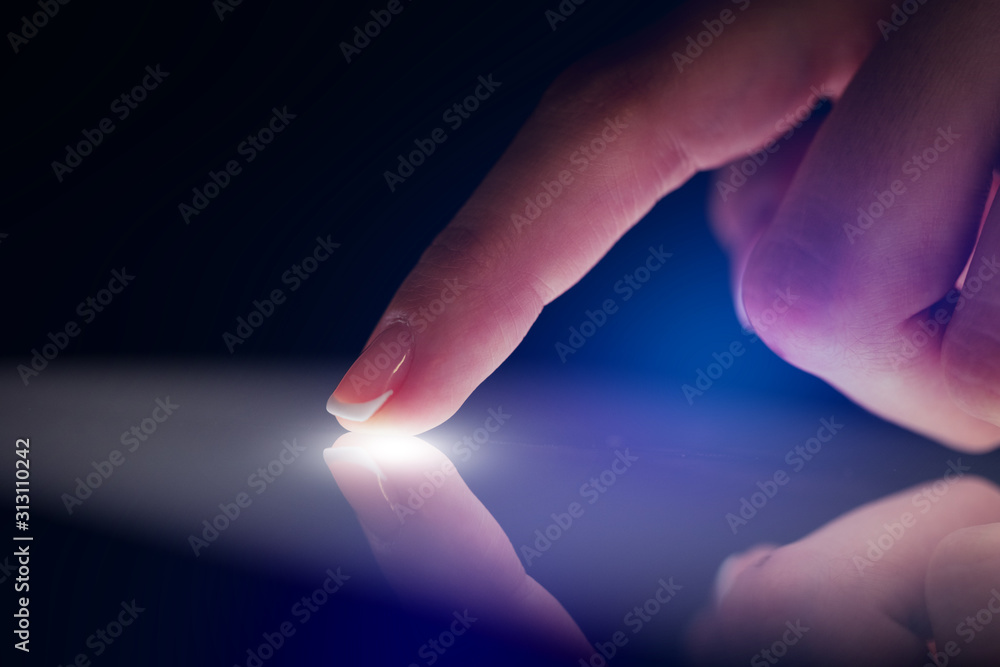 Poster finger touching tablet with dark background with copyspace