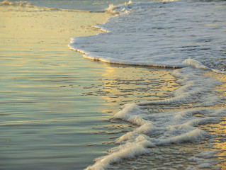 Sunset on the ocean, surf on the beach, beautiful reflection in the water, close up