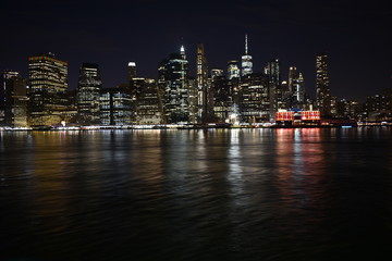 New york skyline from brooklyn at night with water reflection