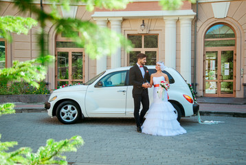 beautiful, loving couple on a wedding walk with a car