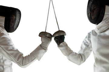Teen girls in fencing costumes with swords in hands isolated on white studio background. Young...