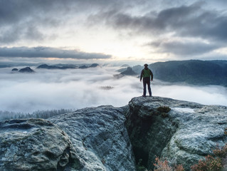 Fototapeta premium Hike in autumn mountains. Man stay above heavy mist in valley